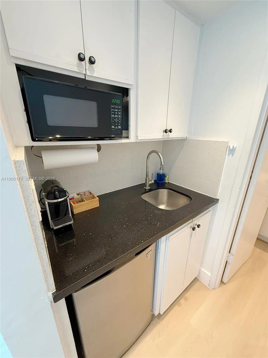 A small kitchenette features white cabinets, a microwave, a sink, and a black countertop — 5445 Collins Ave # 635, Miami Beach FL 33140, MIAMI BEACH, FL