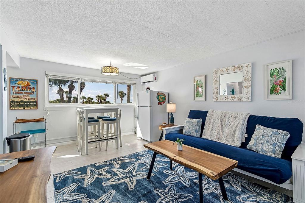 A living room features a blue futon, a wooden coffee table, and a dining set — 11730 GULF BOULEVARD UNIT 29, TREASURE ISLAND, FL