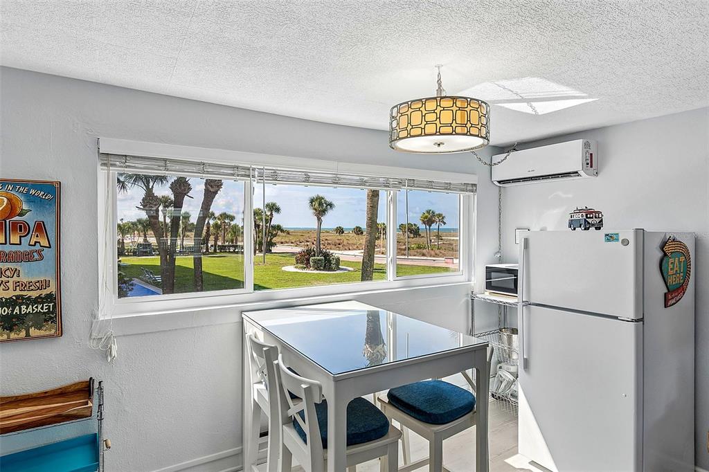 A dining area with a table, chairs, and a window view of the ocean — 11730 GULF BOULEVARD UNIT 29, TREASURE ISLAND, FL