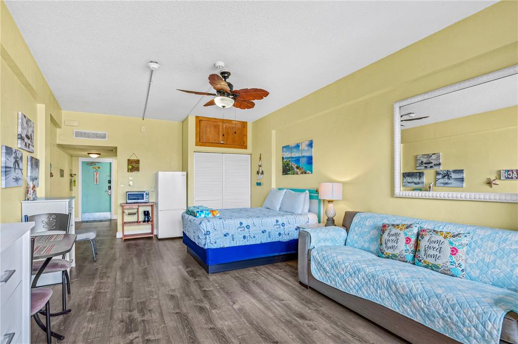 A studio apartment features a bed, a sofa, a kitchenette, and light yellow walls — 2301 S ATLANTIC AVENUE UNIT 126, DAYTONA BEACH, FL
