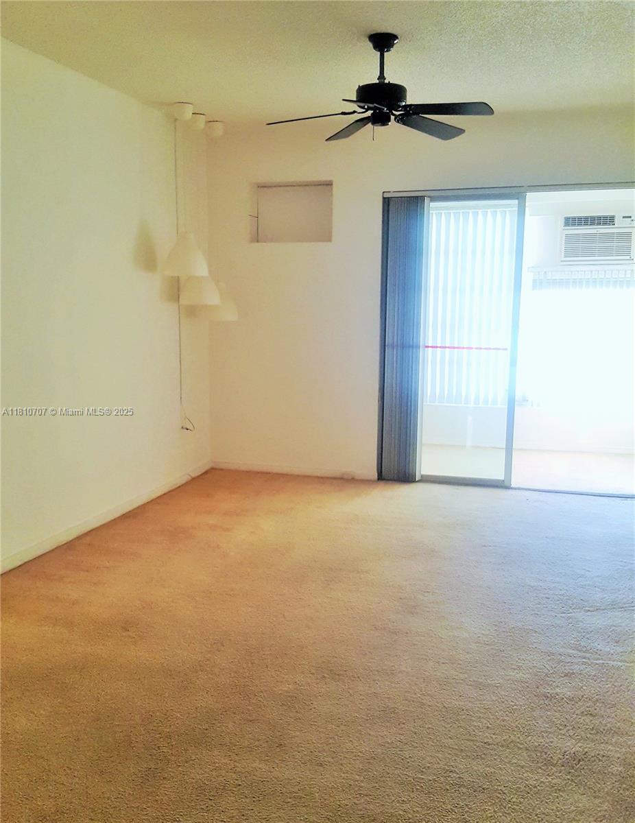 An empty room features beige carpeting, a ceiling fan, and a sliding glass door — 19080 NE 3rd Ct # 318, Miami FL 33179, MIAMI, FL