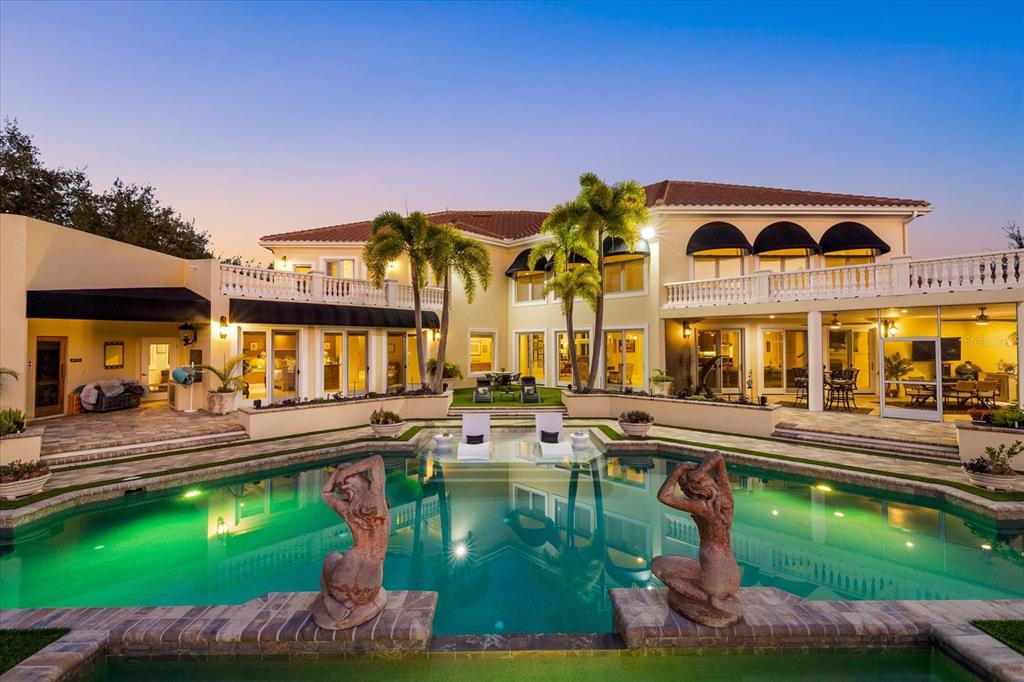 A large two-story house with a swimming pool, palm trees, and a balcony at dusk — 3550 SARASOTA GOLF CLUB BOULEVARD, SARASOTA, FL