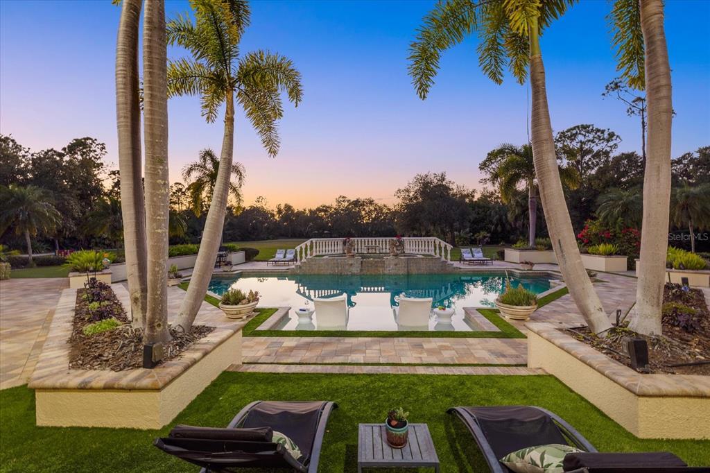 A swimming pool with lounge chairs sits on a patio surrounded by palm trees — 3550 SARASOTA GOLF CLUB BOULEVARD, SARASOTA, FL