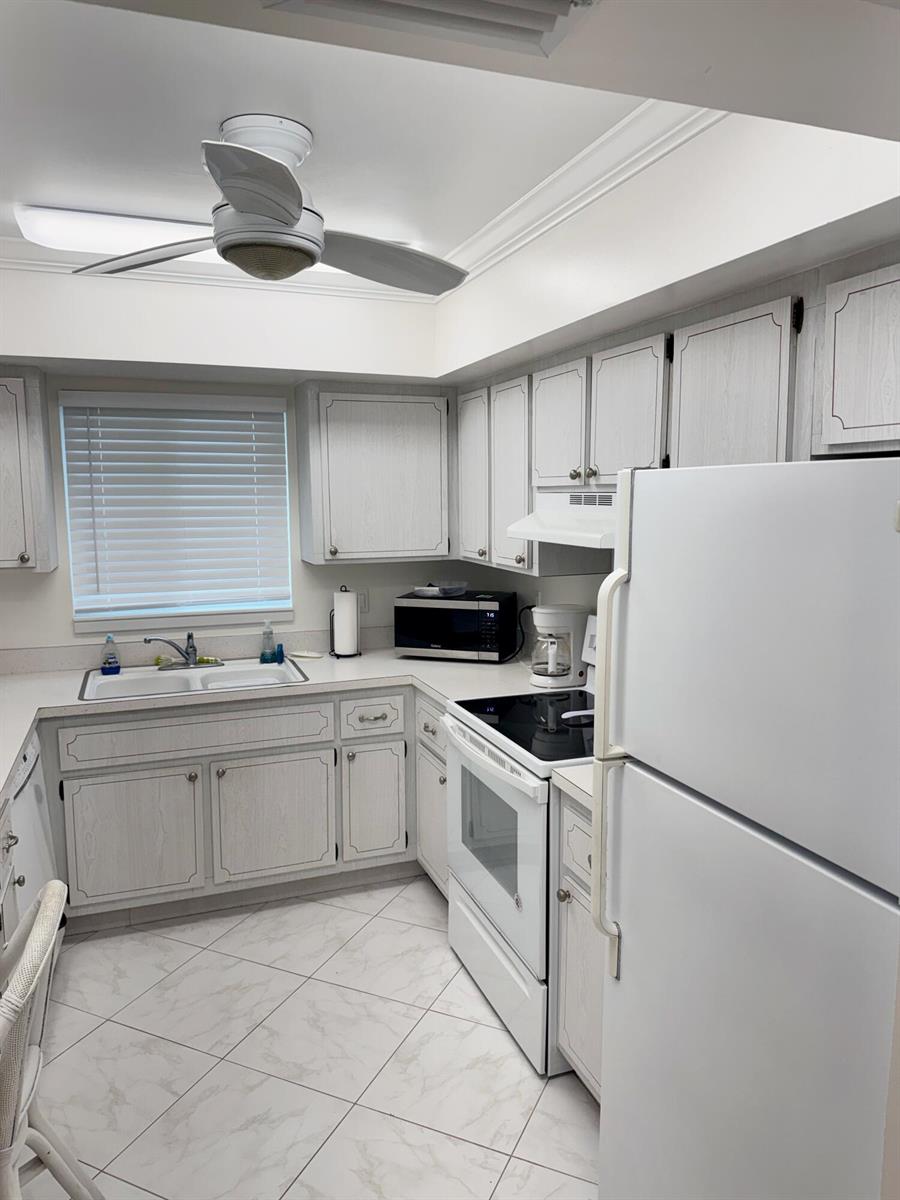 A kitchen features white wood-grain cabinets, white appliances, a ceiling fan, and tiled flooring — 2950 SE Ocean Boulevard # 6, Stuart FL 34996, STUART, FL