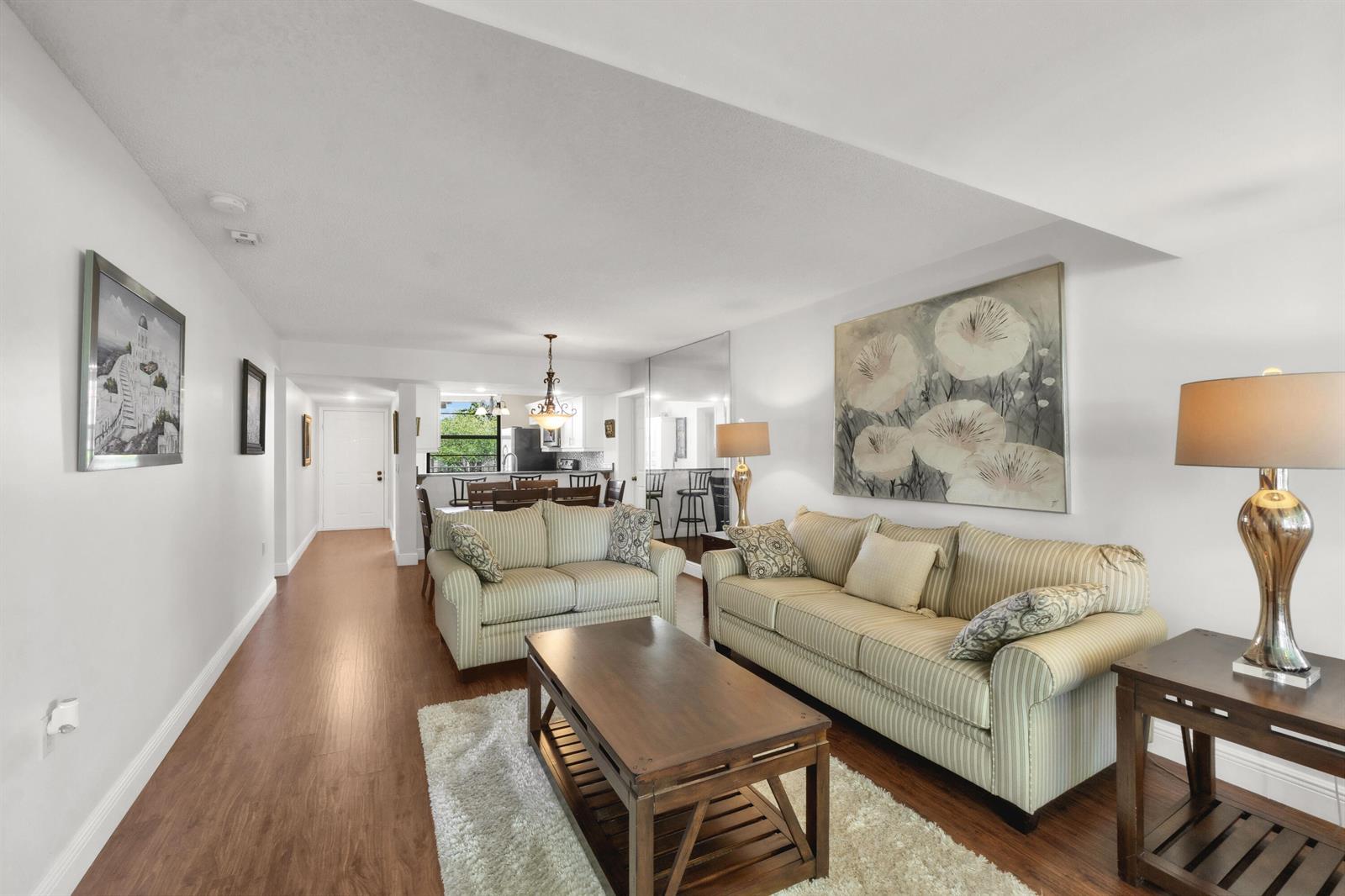 A living room with striped sofas, a wooden coffee table, and wood-look flooring — 3716 Whitehall Drive # 202, West Palm Beach FL 33401, WEST PALM BEACH, FL