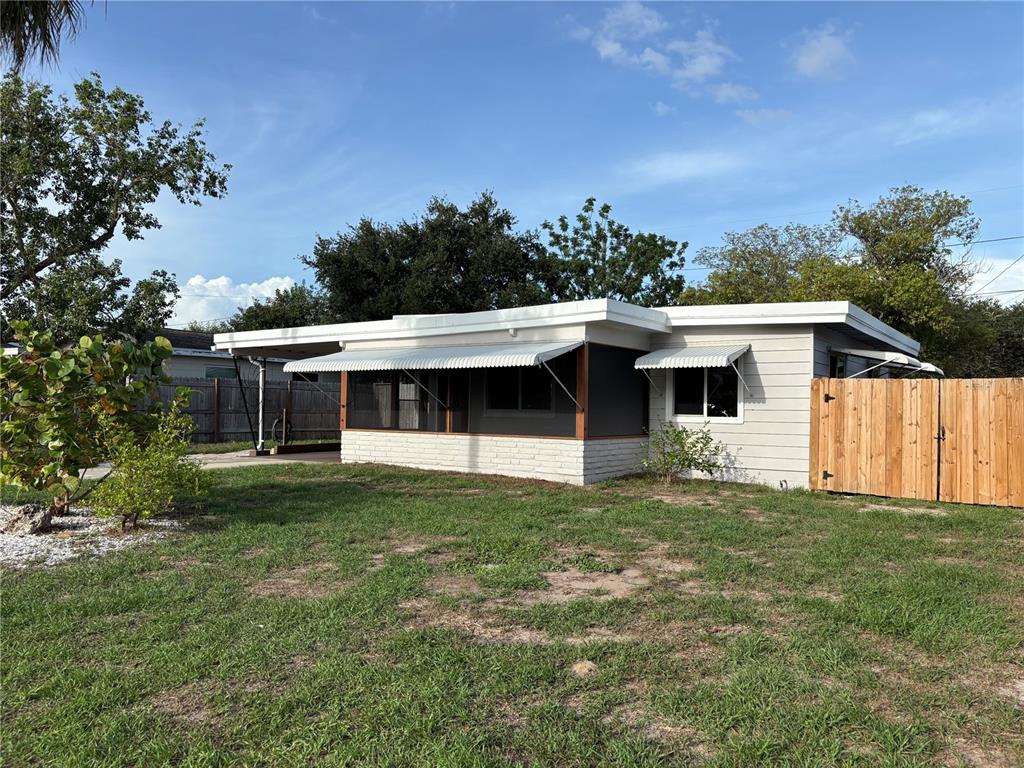 A single-story house with a screened-in porch, white brick base, and a wooden fence — 5165 104TH WAY N, ST PETERSBURG, FL