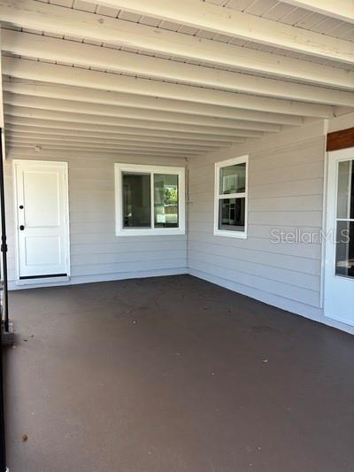 A covered patio features light gray horizontal siding, a concrete floor, and two white doors — 5165 104TH WAY N, ST PETERSBURG, FL