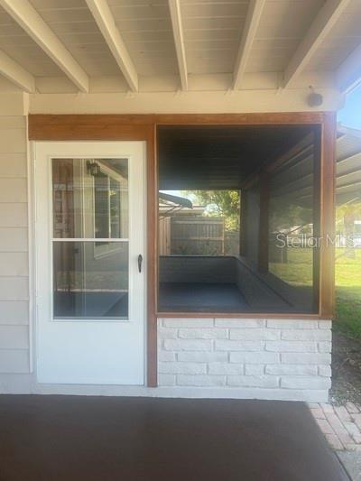 A white door sits next to a screened-in porch with a white brick base — 5165 104TH WAY N, ST PETERSBURG, FL