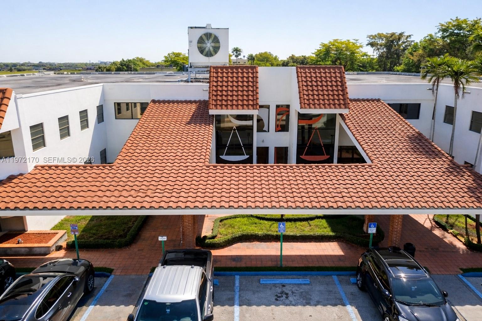 An exterior view of a white building with a large terracotta-tiled portico and parking — 5969 NW 151st St, Miami Lakes FL 33014, MIAMI LAKES, FL