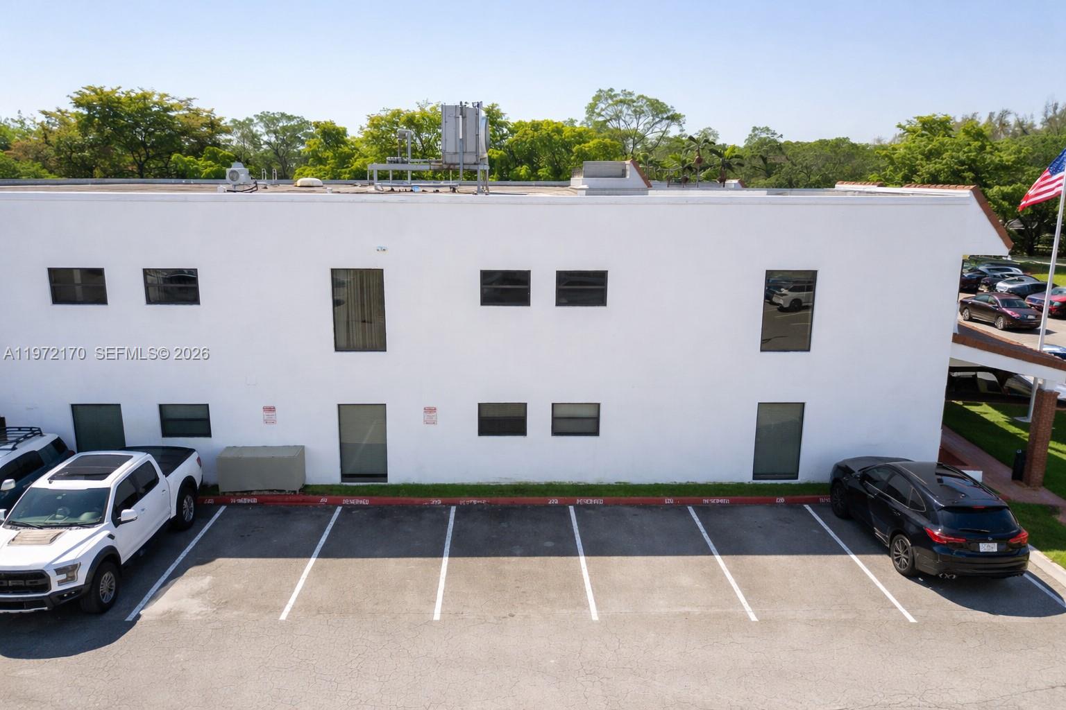 A white two-story commercial building features a parking lot with several reserved spaces — 5969 NW 151st St, Miami Lakes FL 33014, MIAMI LAKES, FL