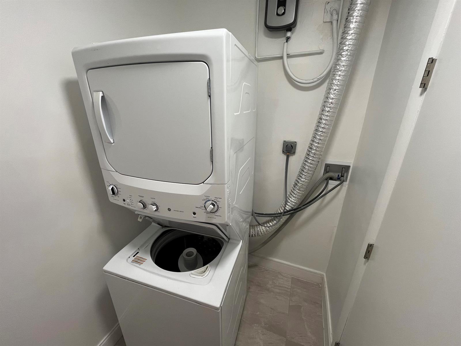 A white stacked washer and dryer unit is installed in a small laundry closet — 1019 SE 3rd Street # 3, Deerfield Beach FL 33441, DEERFIELD BEACH, FL
