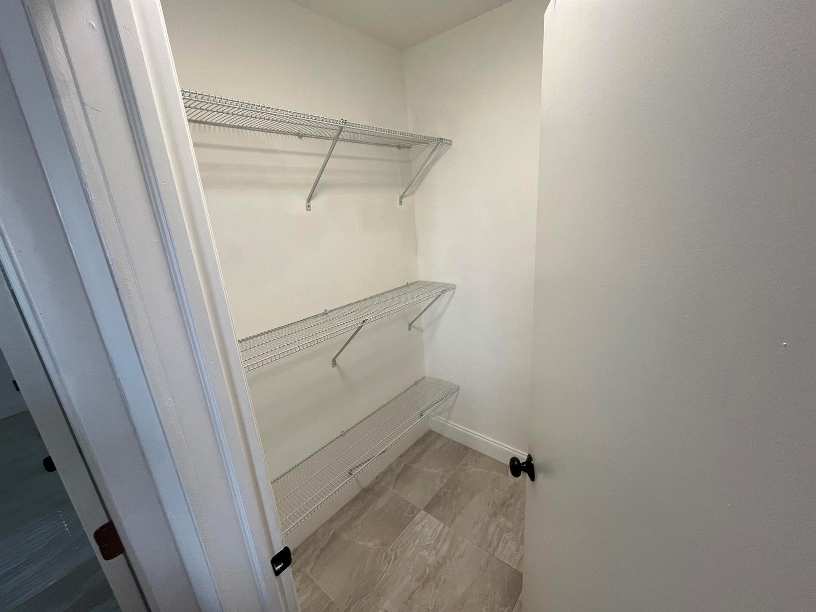 A small closet features three levels of white wire shelving and light-colored tile flooring — 1019 SE 3rd Street # 3, Deerfield Beach FL 33441, DEERFIELD BEACH, FL