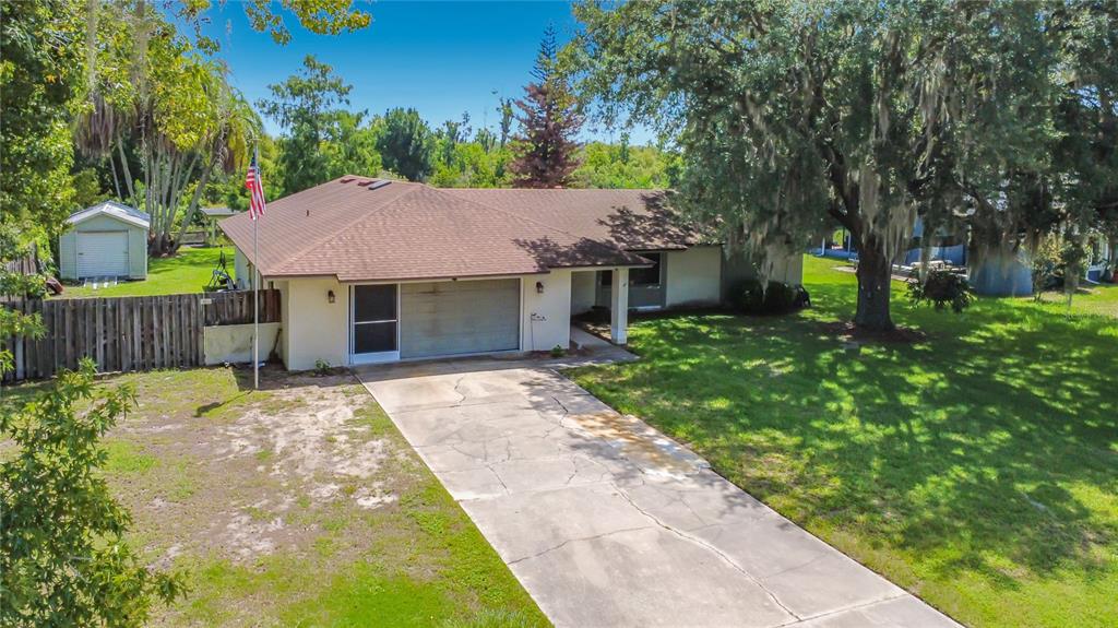 An exterior view of a single-story house with a brown roof, garage, and concrete driveway — 28800 TAMMI DRIVE, TAVARES, FL