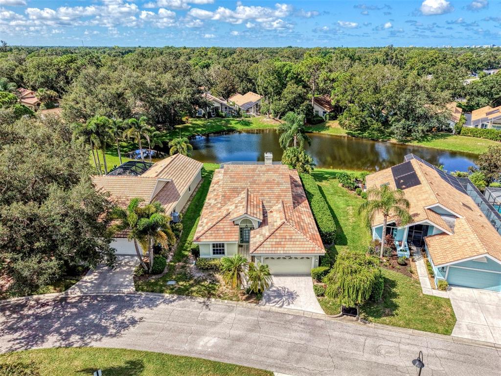 An aerial view of a suburban house with a tiled roof situated by a pond — 4468 ASCOT CIRCLE N, SARASOTA, FL
