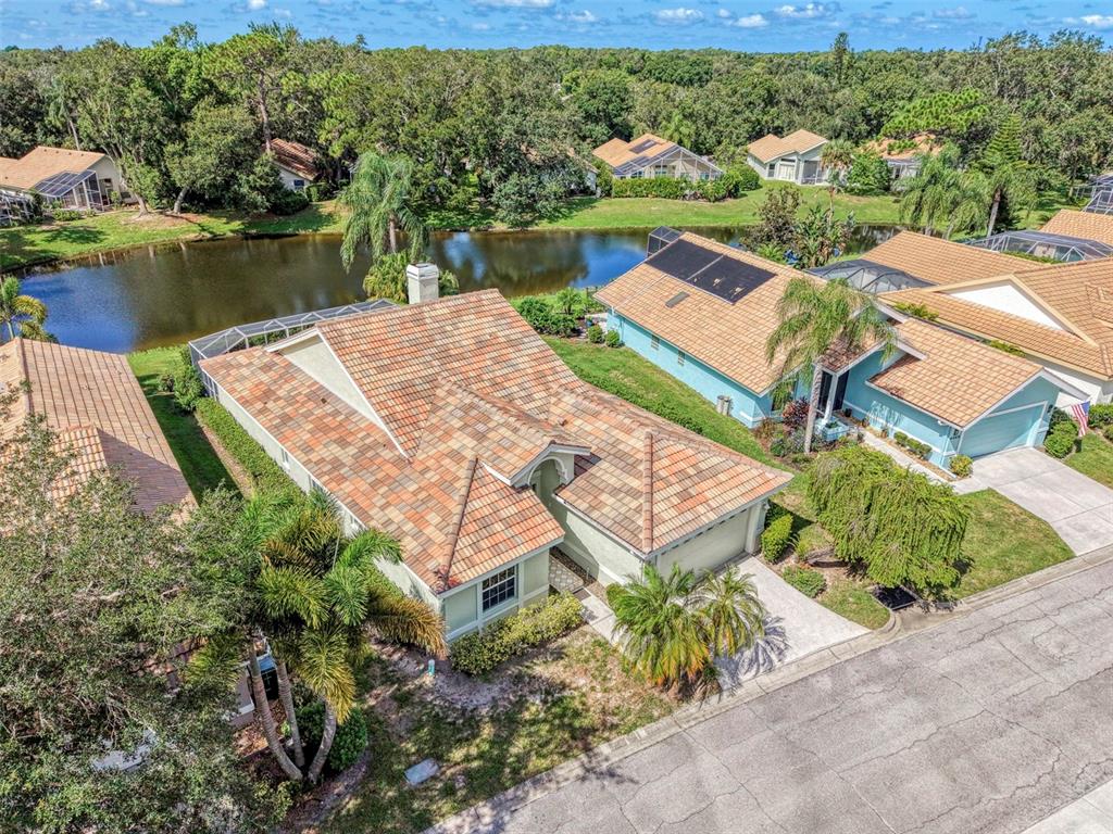 An aerial view shows a suburban house with a tiled roof next to a pond — 4468 ASCOT CIRCLE N, SARASOTA, FL