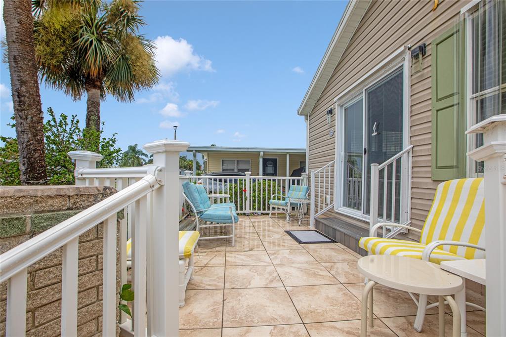 A tiled patio features outdoor furniture, a white railing, and a view of neighboring homes — 2100 KINGS HIGHWAY UNIT 685, PUNTA GORDA, FL