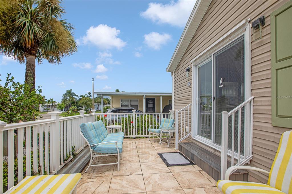 A patio with tiled flooring, white railings, and outdoor furniture sits beside a house exterior — 2100 KINGS HIGHWAY UNIT 685, PUNTA GORDA, FL