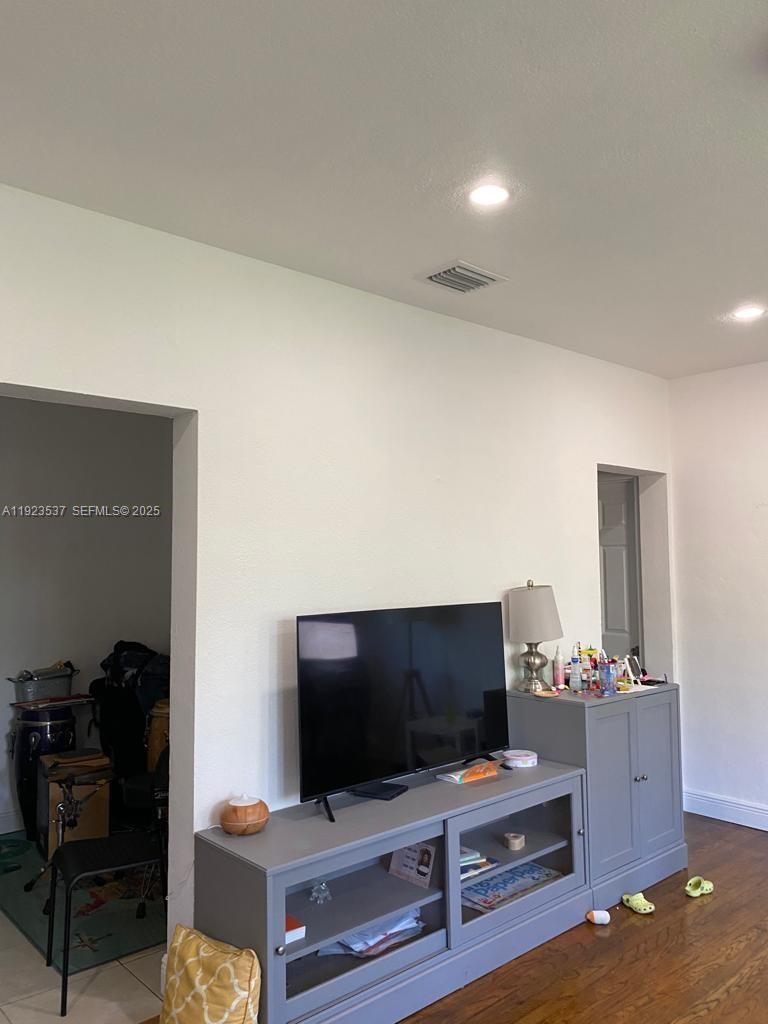 A living room with dark hardwood floors and white walls is viewed through a doorway — 851 80th St, Miami Beach FL 33141, MIAMI BEACH, FL
