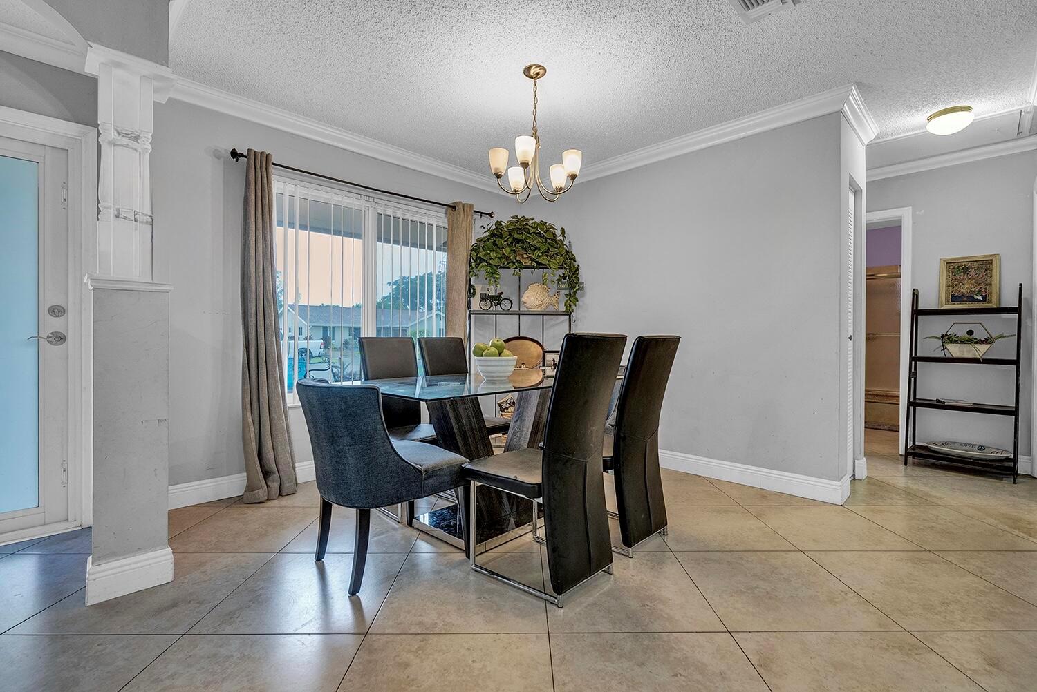 A dining room with a glass table, six chairs, and tile flooring under a chandelier — 9544 Richmond Circle, Boca Raton FL 33434, BOCA RATON, FL
