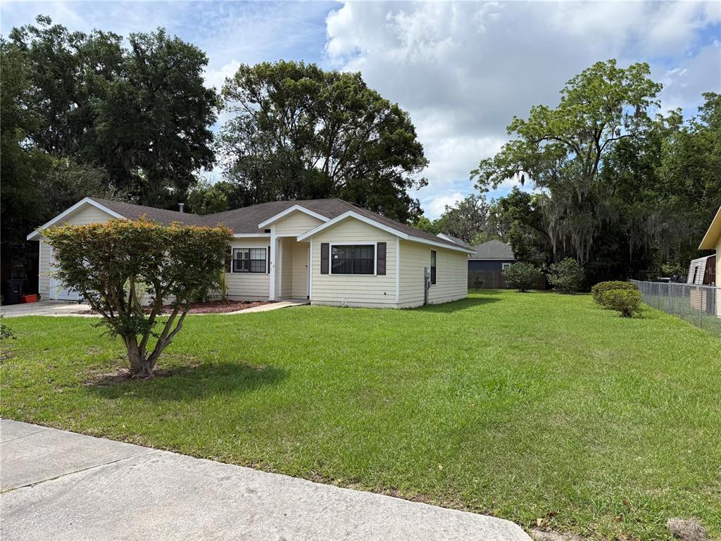 A light yellow, single-story house with a large front yard and mature trees — 821 NW 7TH AVENUE, GAINESVILLE, FL