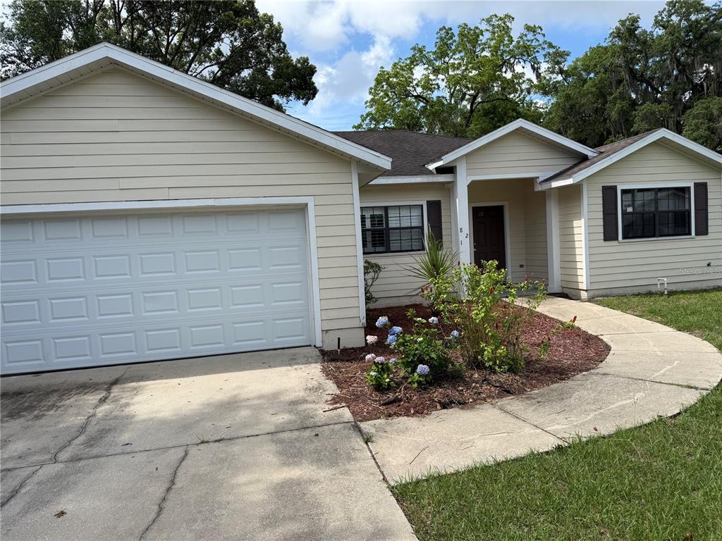 A single-story house with light yellow siding, a two-car garage, and a front walkway — 821 NW 7TH AVENUE, GAINESVILLE, FL