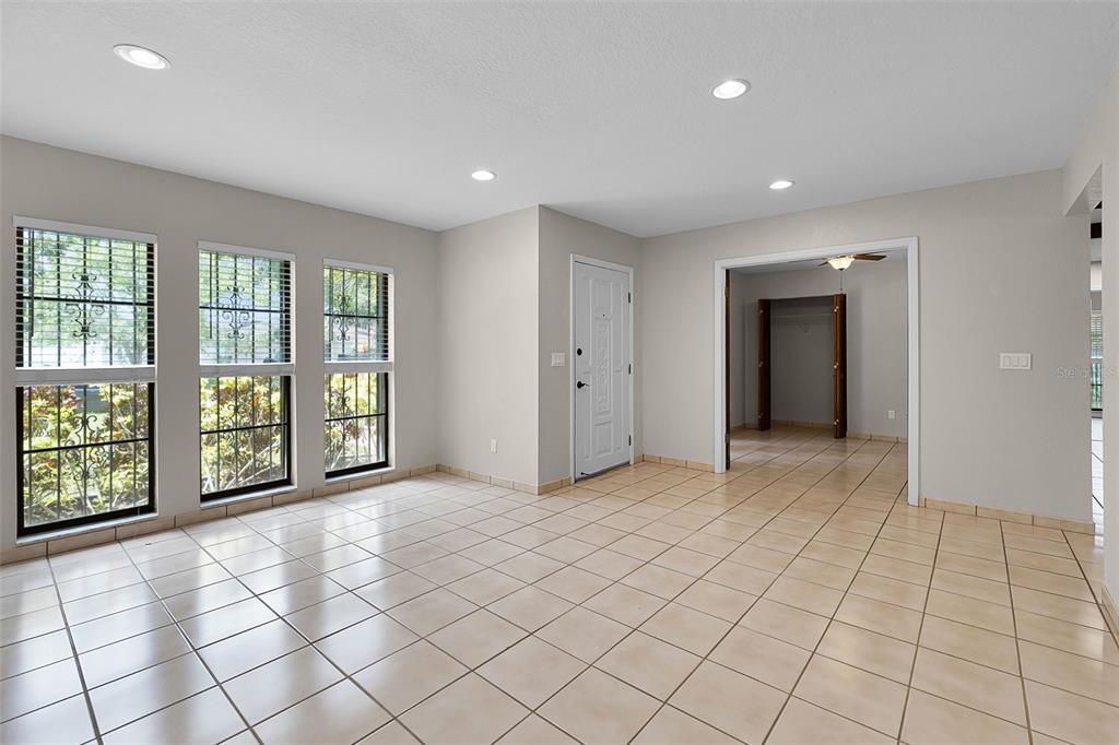 A bright room with light-colored tile flooring, white walls, and three large windows — 8208 LA SERENA DRIVE, TAMPA, FL