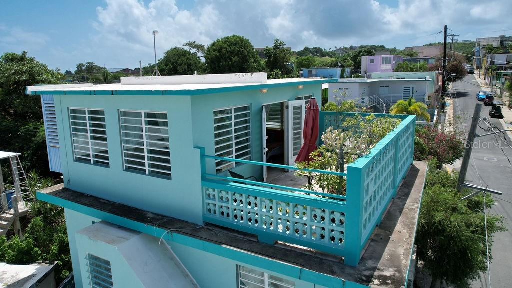 An elevated view of a turquoise house featuring a rooftop terrace with a decorative railing — 220 CALLE PRUDENCIO QUIÑONES, VIEQUES, PR