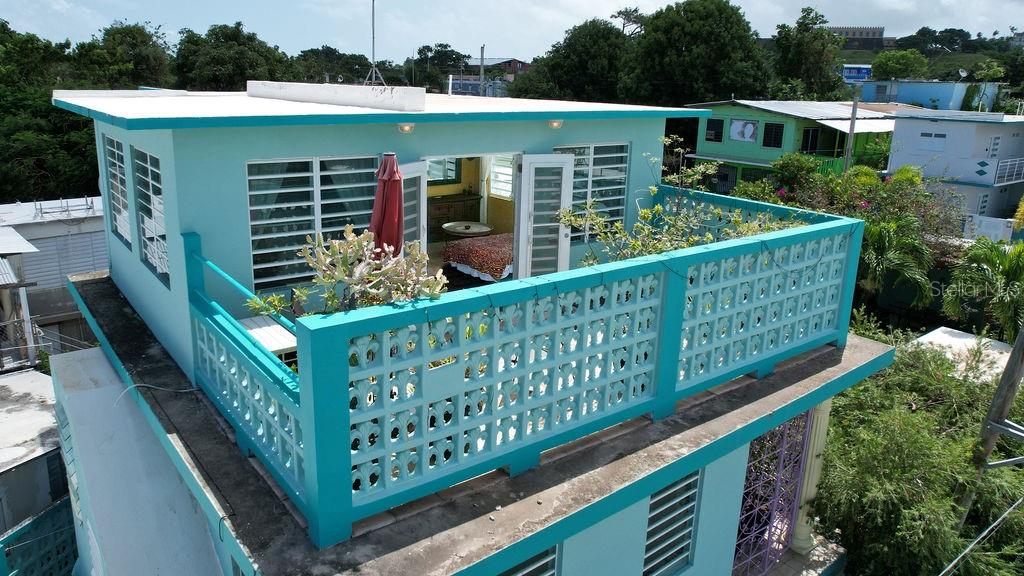 An elevated turquoise terrace with a decorative concrete railing overlooks a room with glass doors — 220 CALLE PRUDENCIO QUIÑONES, VIEQUES, PR