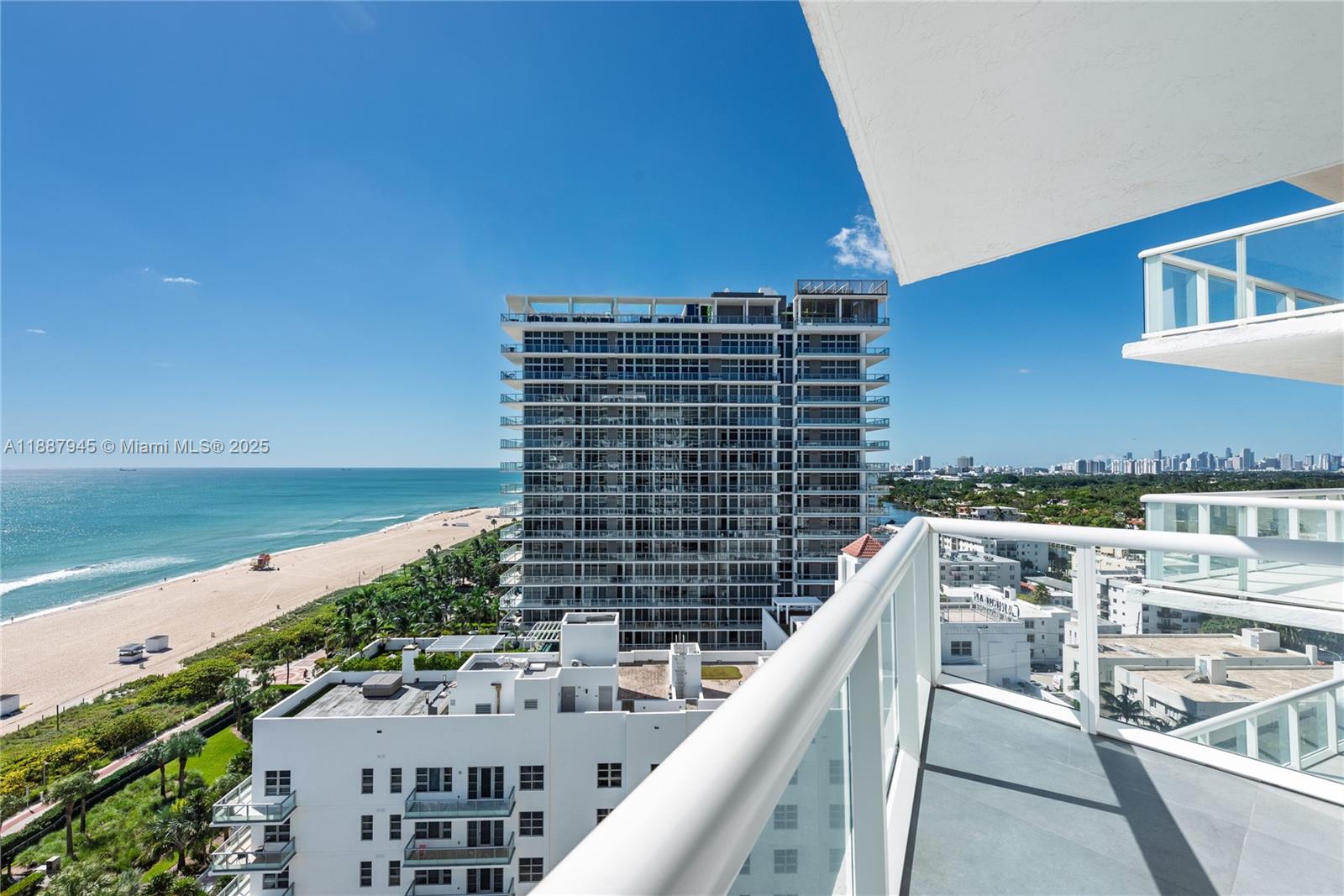 A high-angle view from a balcony overlooking a beach, ocean, and nearby high-rise buildings — 3801 Collins Ave # 1502, Miami Beach FL 33140, MIAMI BEACH, FL