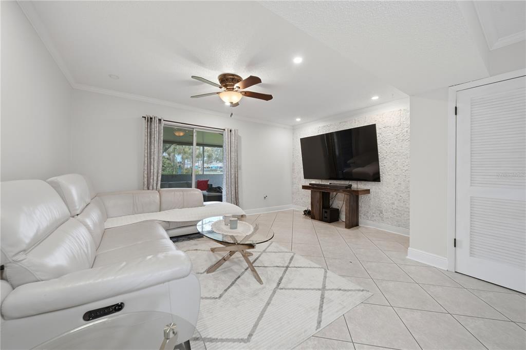 A living room features a white leather sectional, a glass coffee table, and a wall-mounted television — 182 115TH AVENUE N UNIT 182, ST PETERSBURG, FL