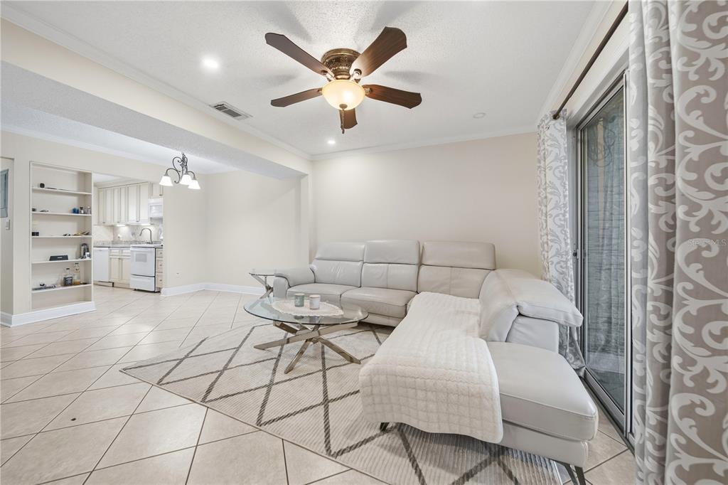 A living room with a white sectional sofa, glass coffee table, and tile flooring — 182 115TH AVENUE N UNIT 182, ST PETERSBURG, FL