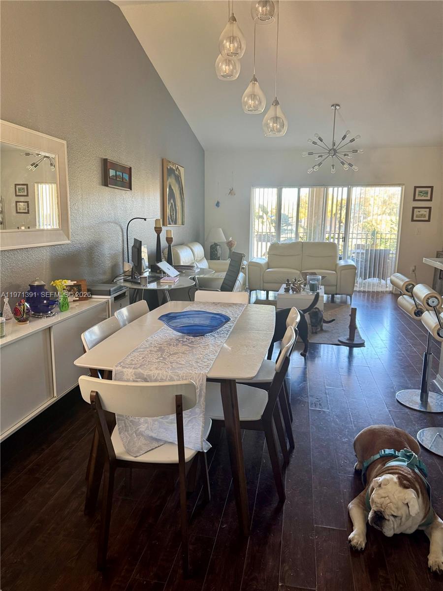A dining area and living room with hardwood floors, vaulted ceilings, and a pet dog — 2517 Centergate Dr # 203, Miramar FL 33025, MIRAMAR, FL