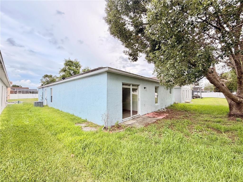 The exterior of a light blue house features a sliding glass door and a large tree — 426 WOODBURY PINES CIRCLE, ORLANDO, FL