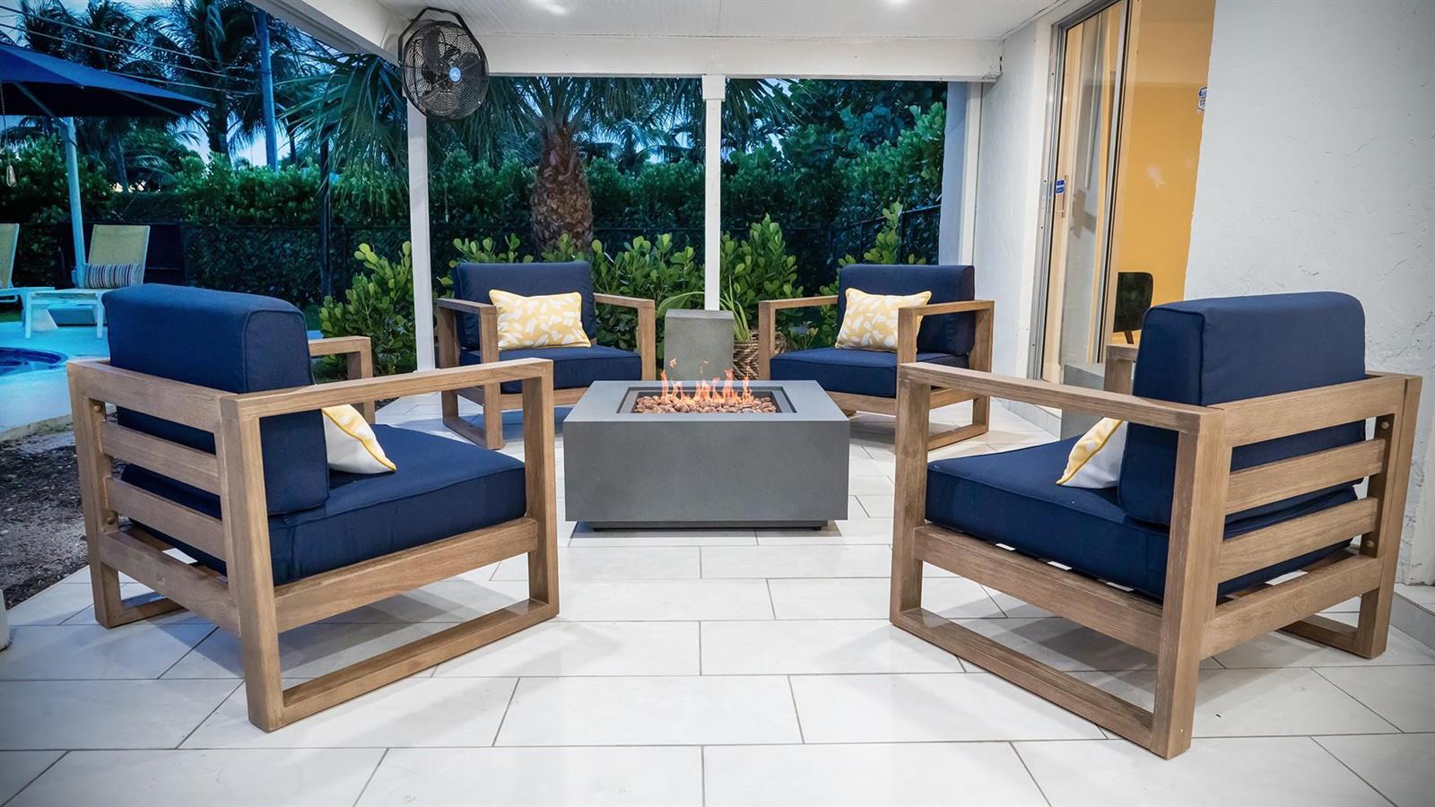 A patio features four wooden armchairs with navy cushions surrounding a square gas fire pit — 518 Sunshine Drive, Delray Beach FL 33444, DELRAY BEACH, FL