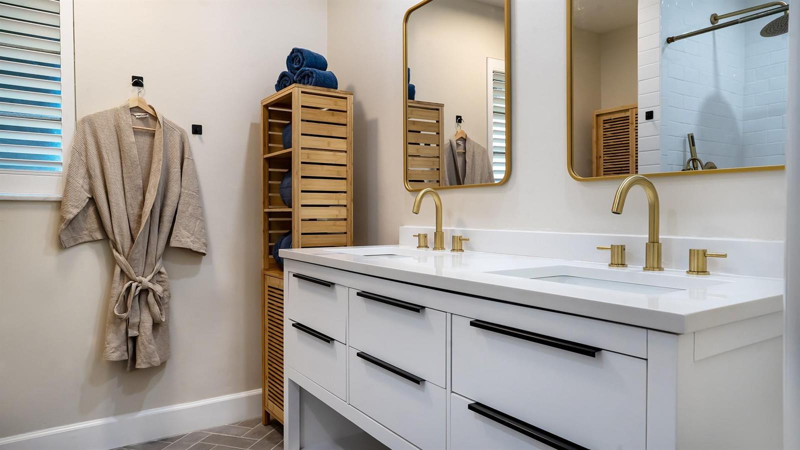 A modern bathroom features a white double vanity with gold faucets and black drawer pulls — 518 Sunshine Drive, Delray Beach FL 33444, DELRAY BEACH, FL