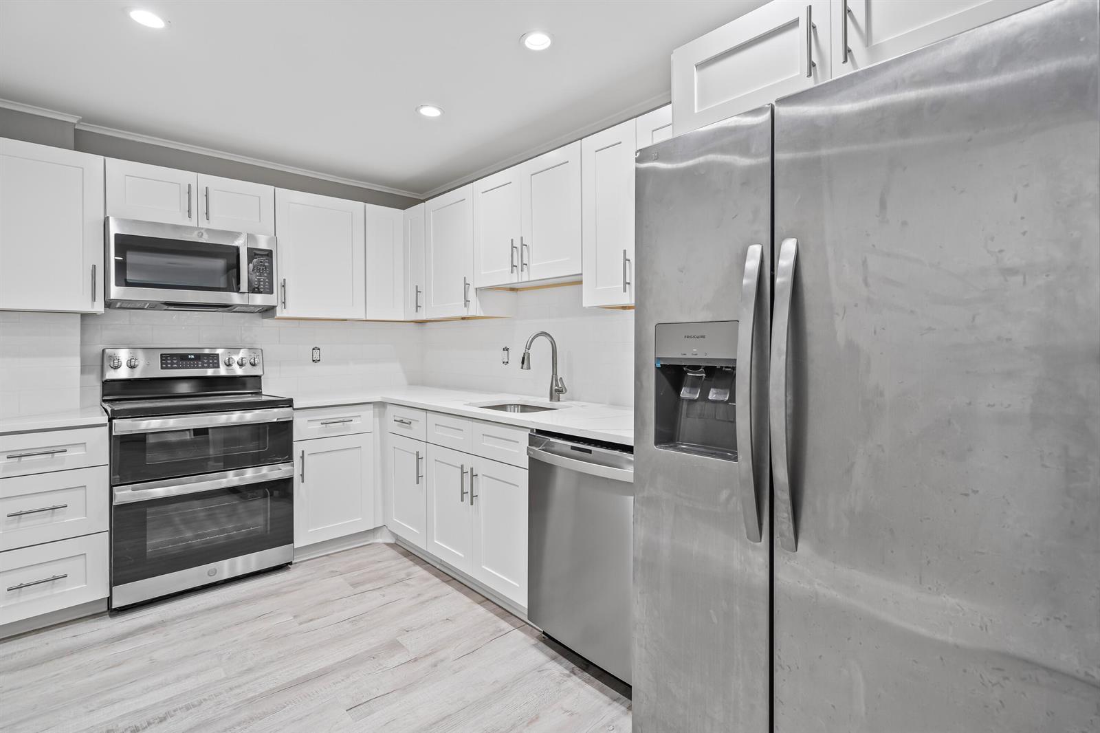 A kitchen featuring white cabinets, stainless steel appliances, and light-colored wood-look flooring — 2851 S Ocean # 0026, Boca Raton FL 33432, BOCA RATON, FL