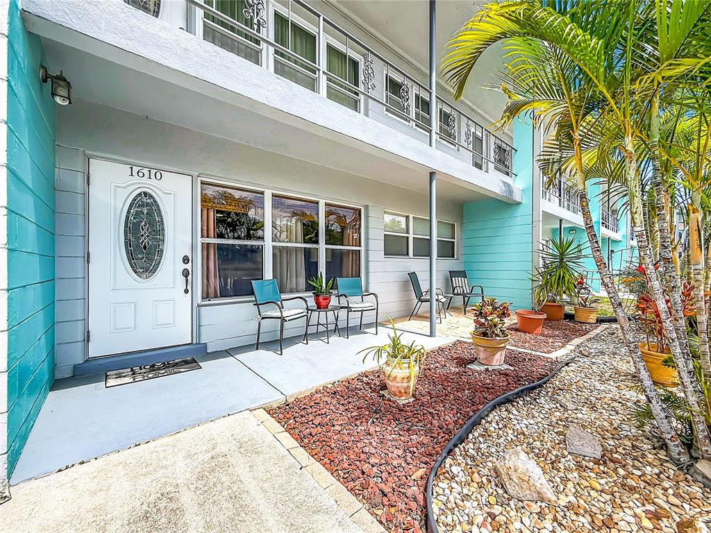 The exterior of a two-story building features a white front door, patio seating, and landscaping — 5861 42ND TERRACE N UNIT 1610, KENNETH CITY, FL