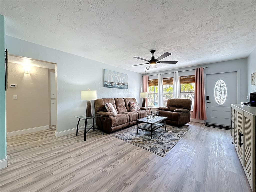 A living room features light wood-look flooring, a brown sofa, a recliner, and a ceiling fan — 5861 42ND TERRACE N UNIT 1610, KENNETH CITY, FL