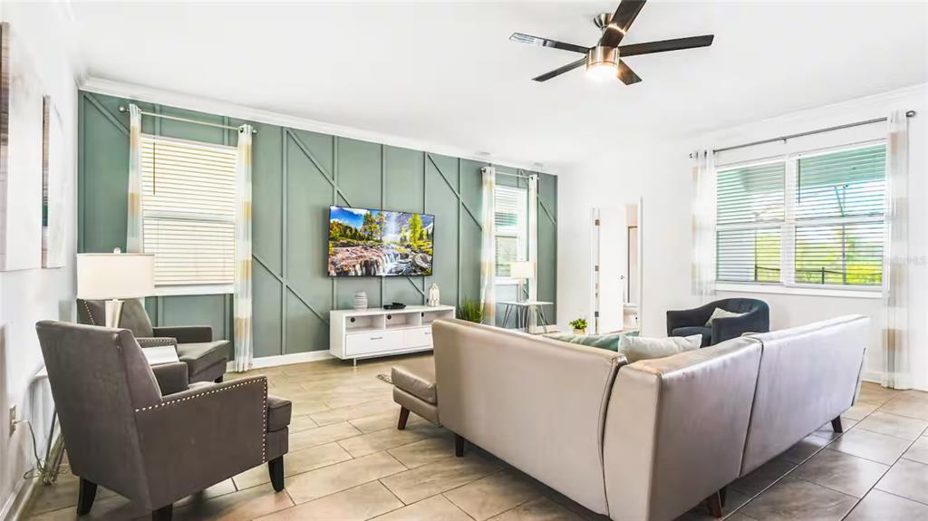 A living room features a sage green accent wall with board and batten trim — 2916 SIMILE STREET, KISSIMMEE, FL