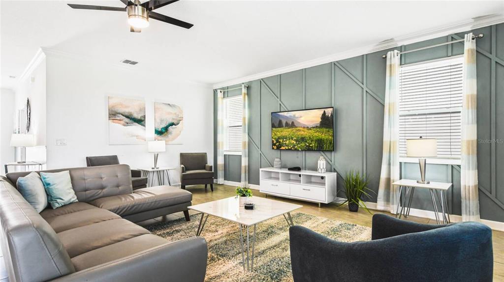 A living room features a gray sectional sofa, a patterned accent wall, and a television — 2916 SIMILE STREET, KISSIMMEE, FL