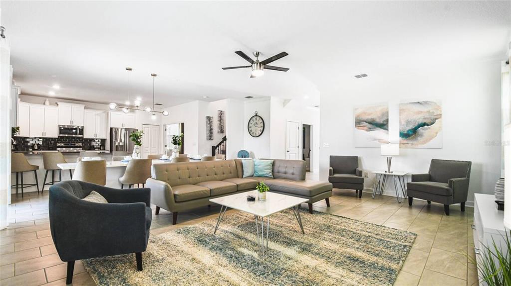 An open-concept living room features a sectional sofa, a coffee table, and an adjacent kitchen — 2916 SIMILE STREET, KISSIMMEE, FL