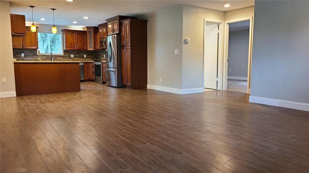 A kitchen with dark wood cabinets and stainless steel appliances opens to a living area — 1718 CARDINAL DR, CLEARWATER, FL