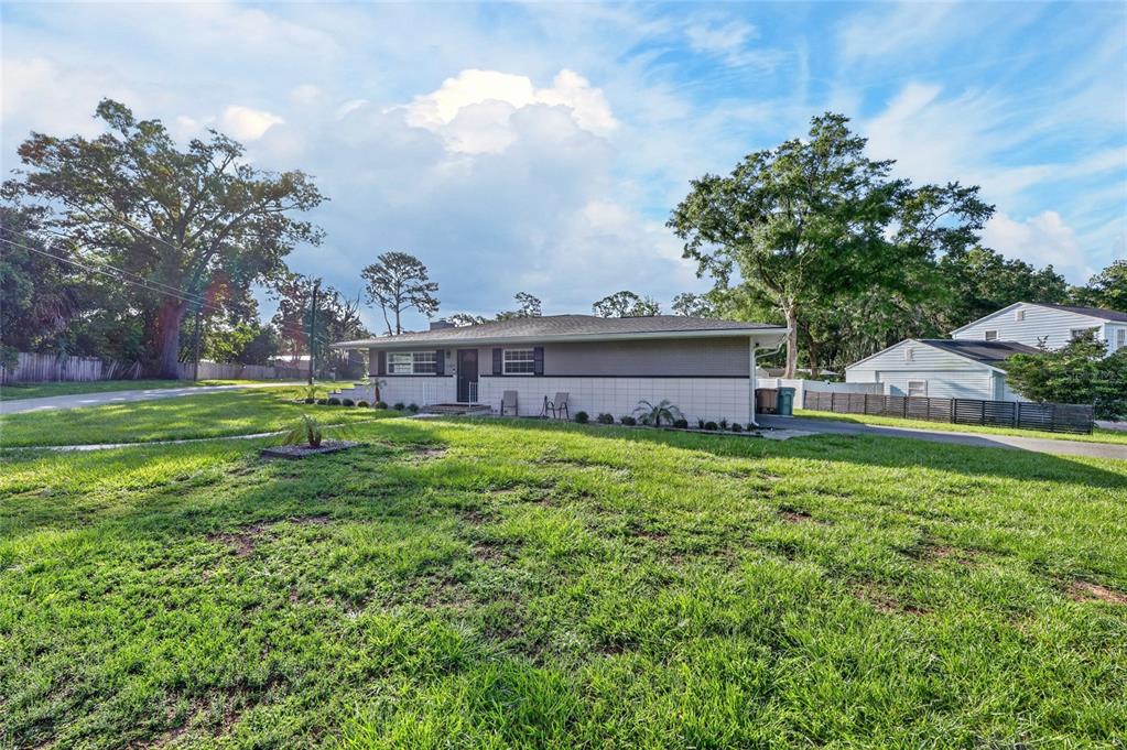 A single-story house with a gray exterior and a large front lawn under a blue sky — 3408 SE 13TH PLACE, OCALA, FL