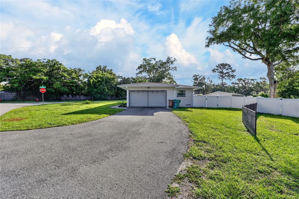 A detached garage with a paved driveway sits on a grassy lot with white fencing — 3408 SE 13TH PLACE, OCALA, FL