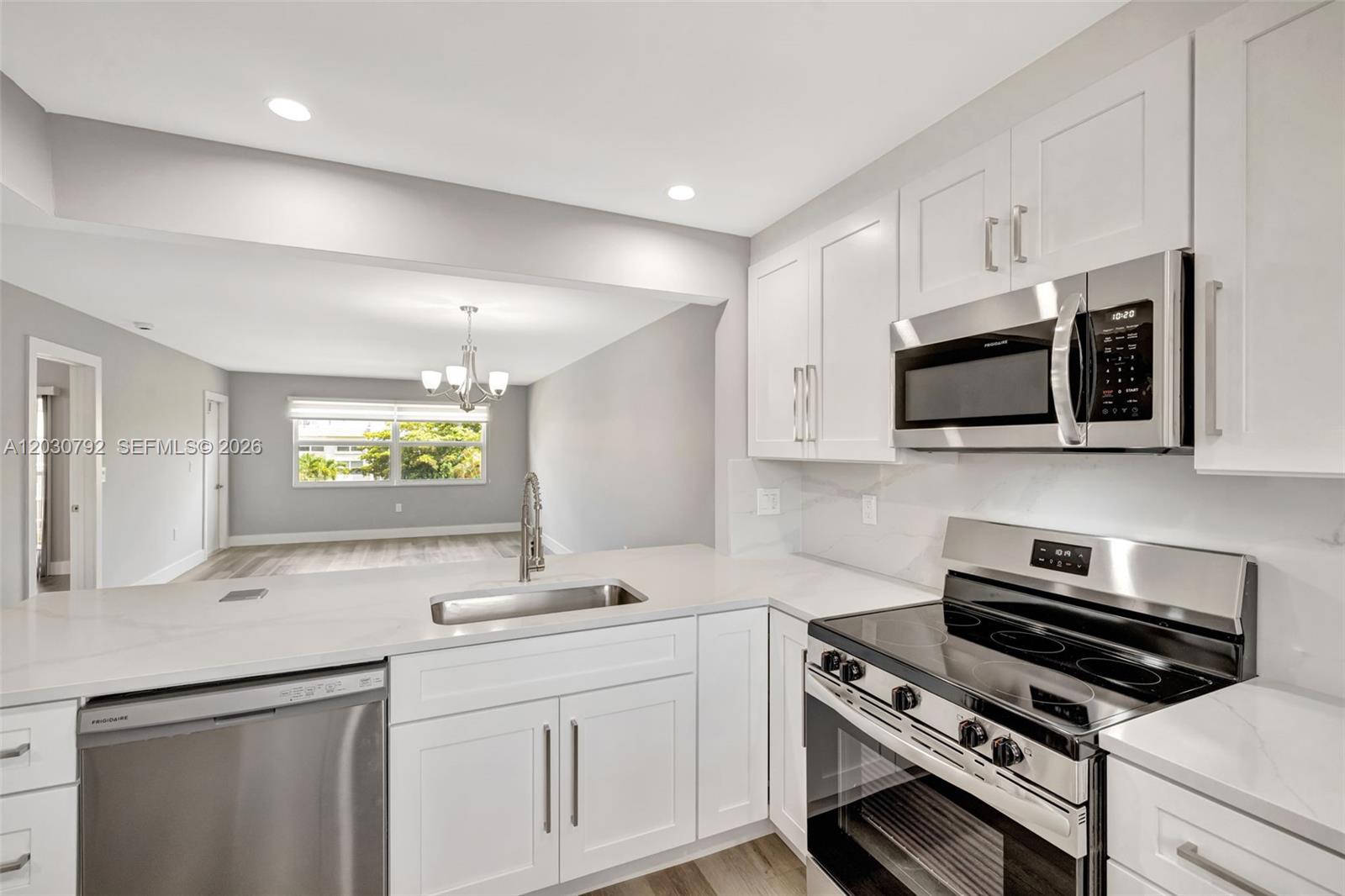 A modern kitchen features white cabinets, stainless steel appliances, and quartz countertops — 6800 Royal Palm Blvd # 302F, Margate FL 33063, MARGATE, FL