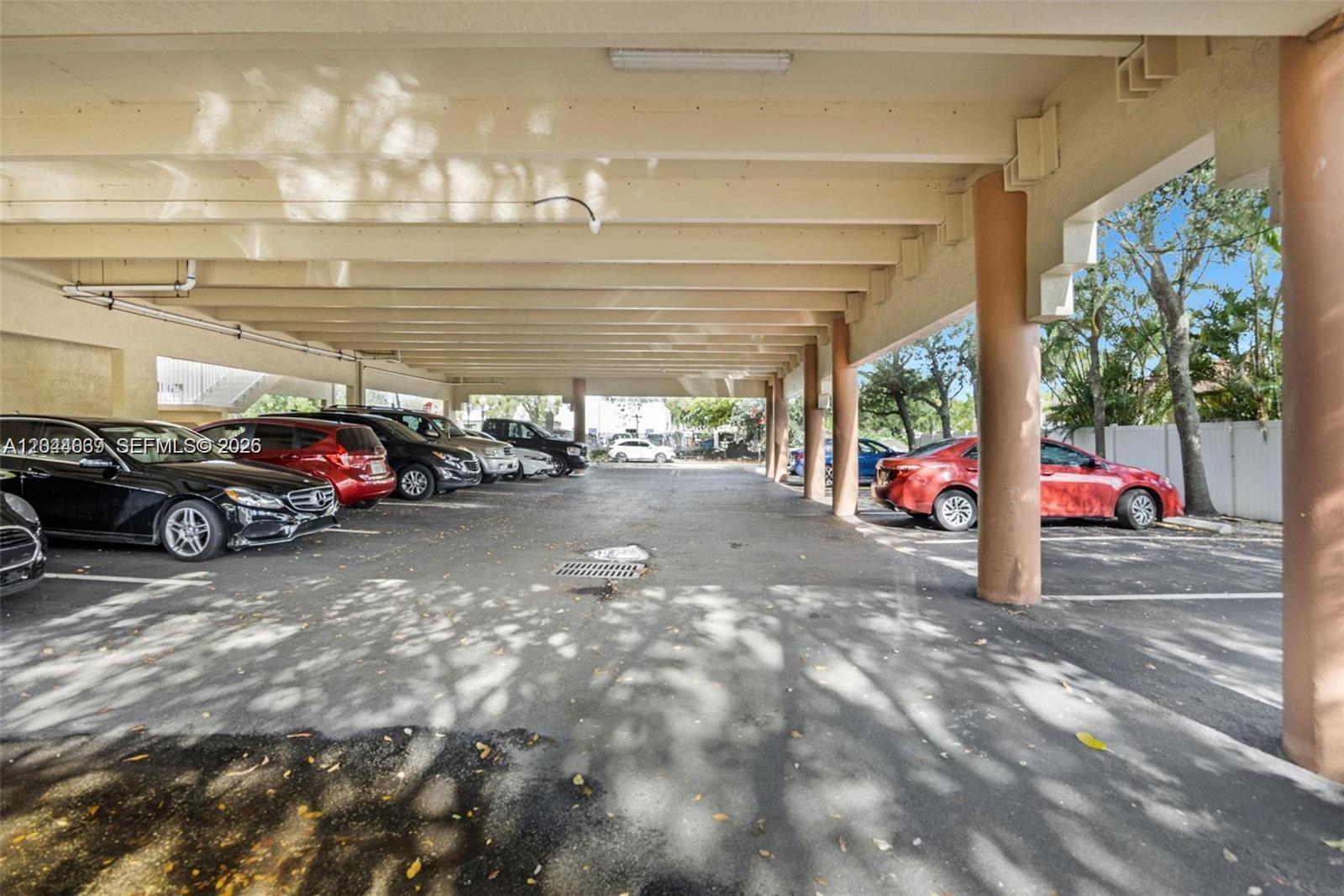 A covered parking area features concrete columns and multiple parked vehicles under a roof — 5595 Orange Dr # 101, Davie FL 33314, DAVIE, FL