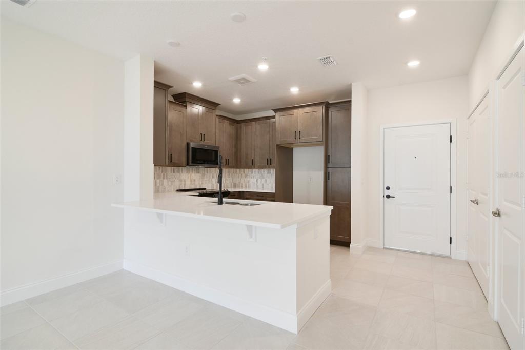 A kitchen features a white island, dark wood cabinets, and light tile flooring — 7557 LAUREATE BOULEVARD UNIT 6301, ORLANDO, FL