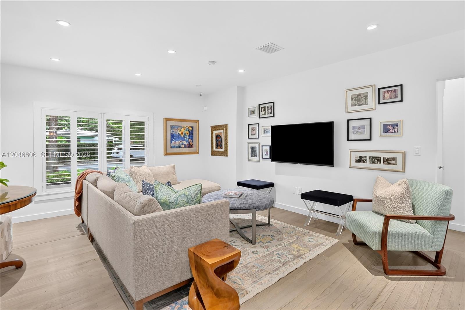 A living room features a sectional sofa, a television, and a patterned area rug — 100 Sarto Ave., Coral Gables FL 33134, CORAL GABLES, FL
