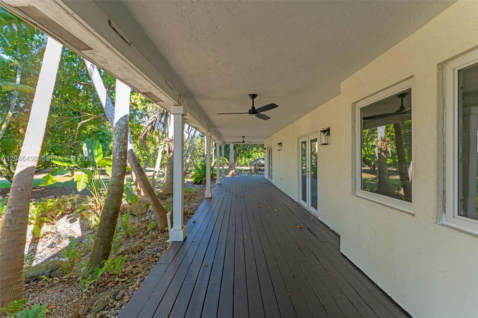 A covered wooden deck runs along the side of a house with white walls — 20076 SW 190th St, Miami FL 33187, MIAMI, FL