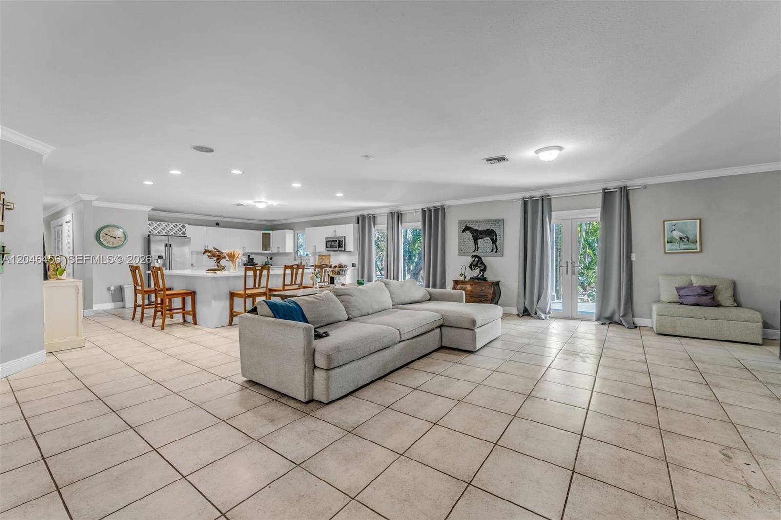 A spacious open-concept living room features a large sectional sofa, tile flooring, and a kitchen — 20076 SW 190th St, Miami FL 33187, MIAMI, FL